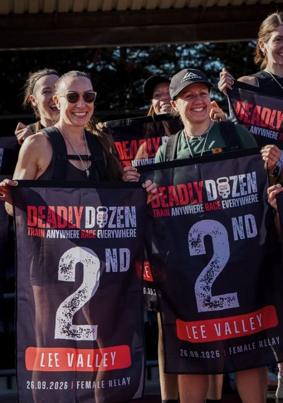 Female relay team celebrating 2nd place with Deadly Dozen flags at Lee Valley